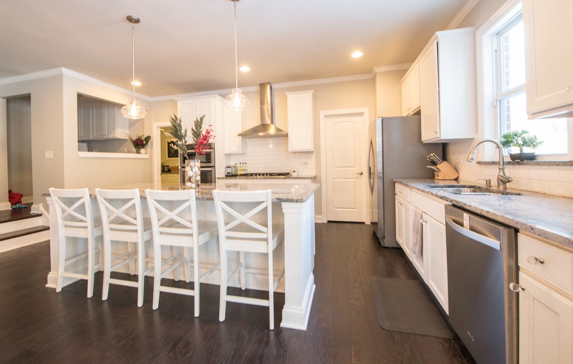 Bright modern kitchen with white cabinets, island seating, and dark wood floors