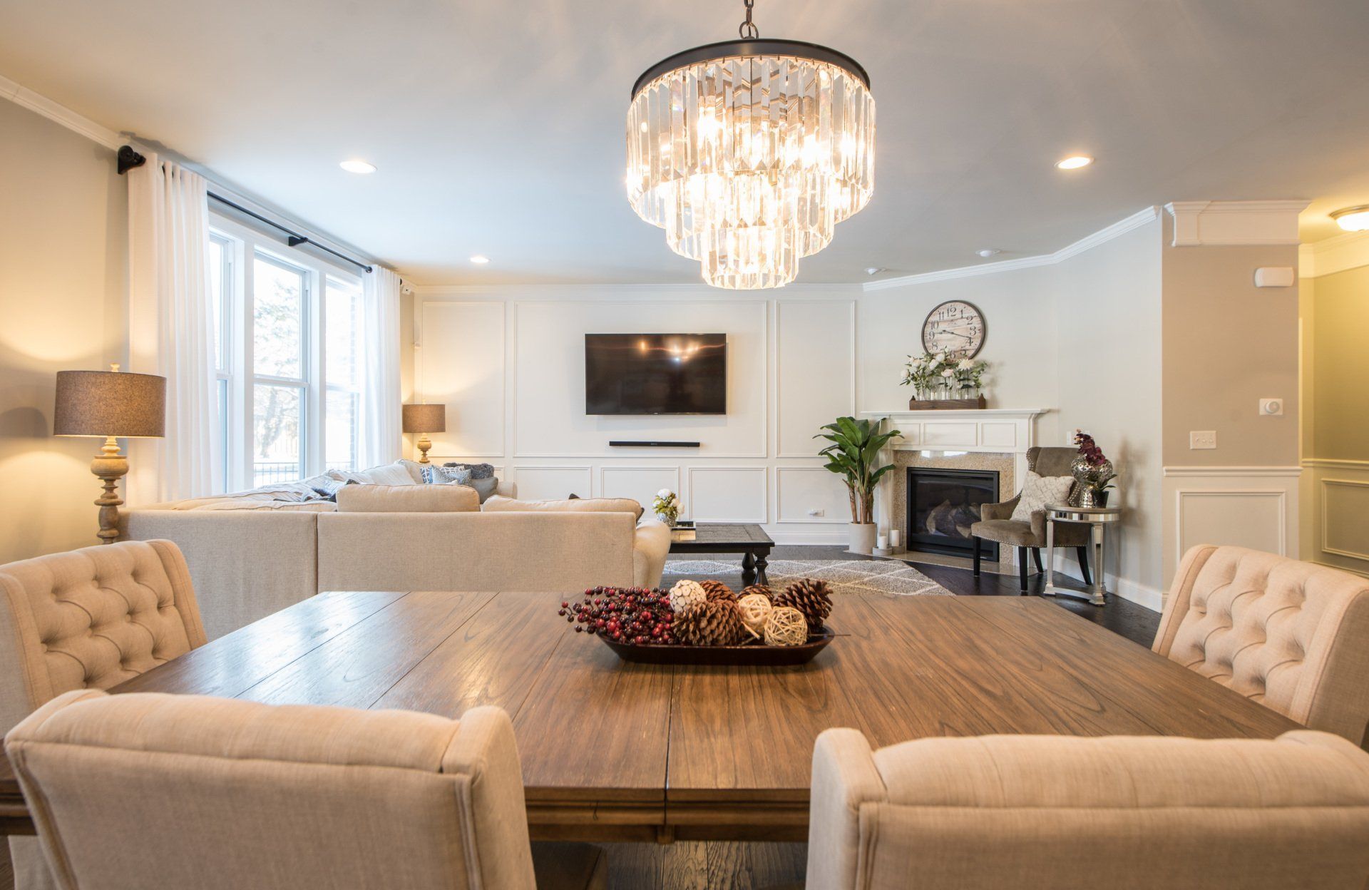 Elegant dining room with a wooden table, beige chairs, crystal chandelier, and fireplace