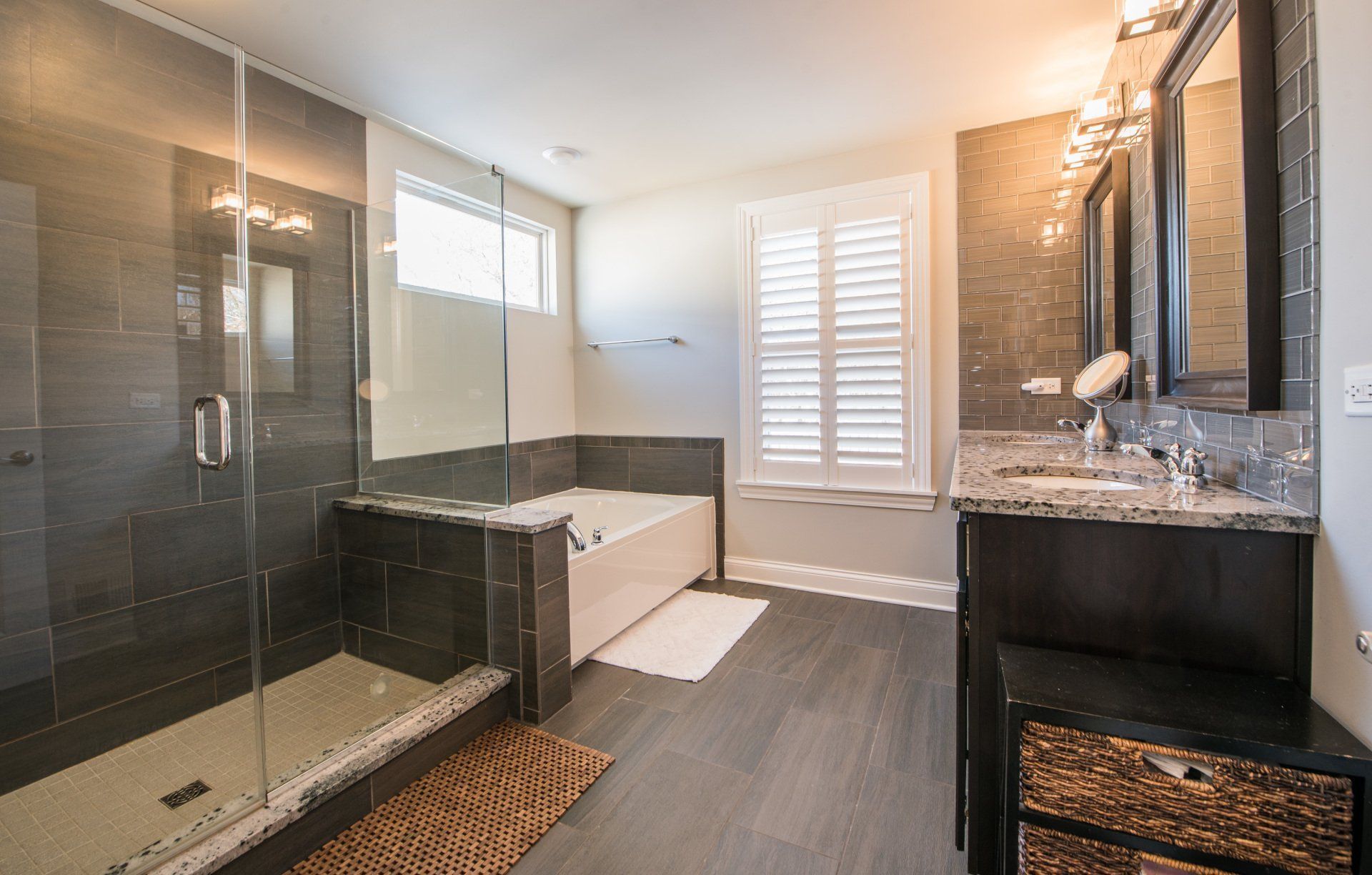 Modern bathroom with glass shower, soaking tub, vanity, and large window blinds