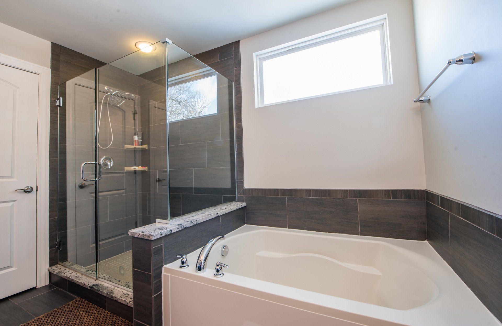 Modern bathroom with a glass shower, soaking tub, and gray tile accents