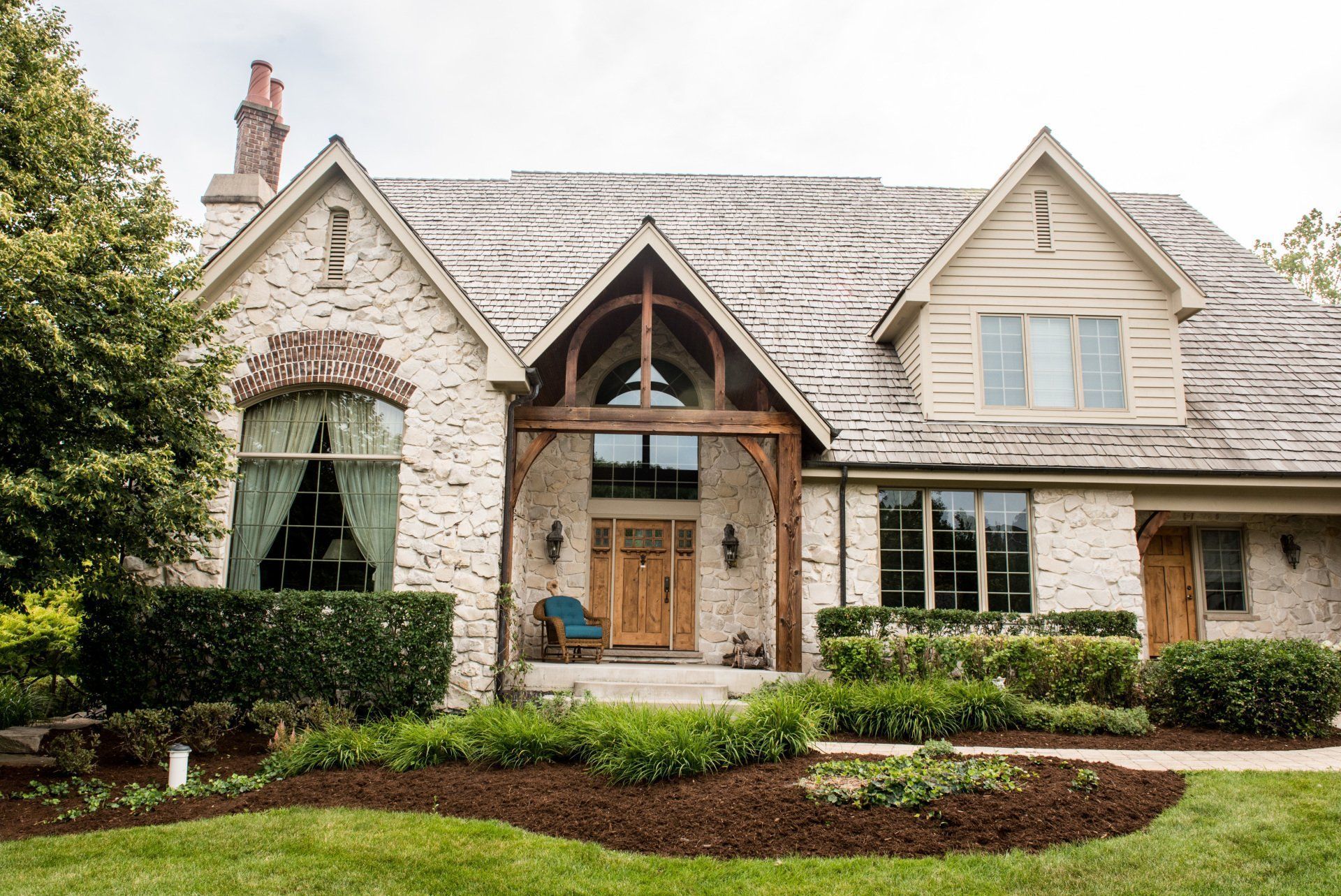 Stone cottage-style house with a steep roof, arched entry, and landscaped front yard