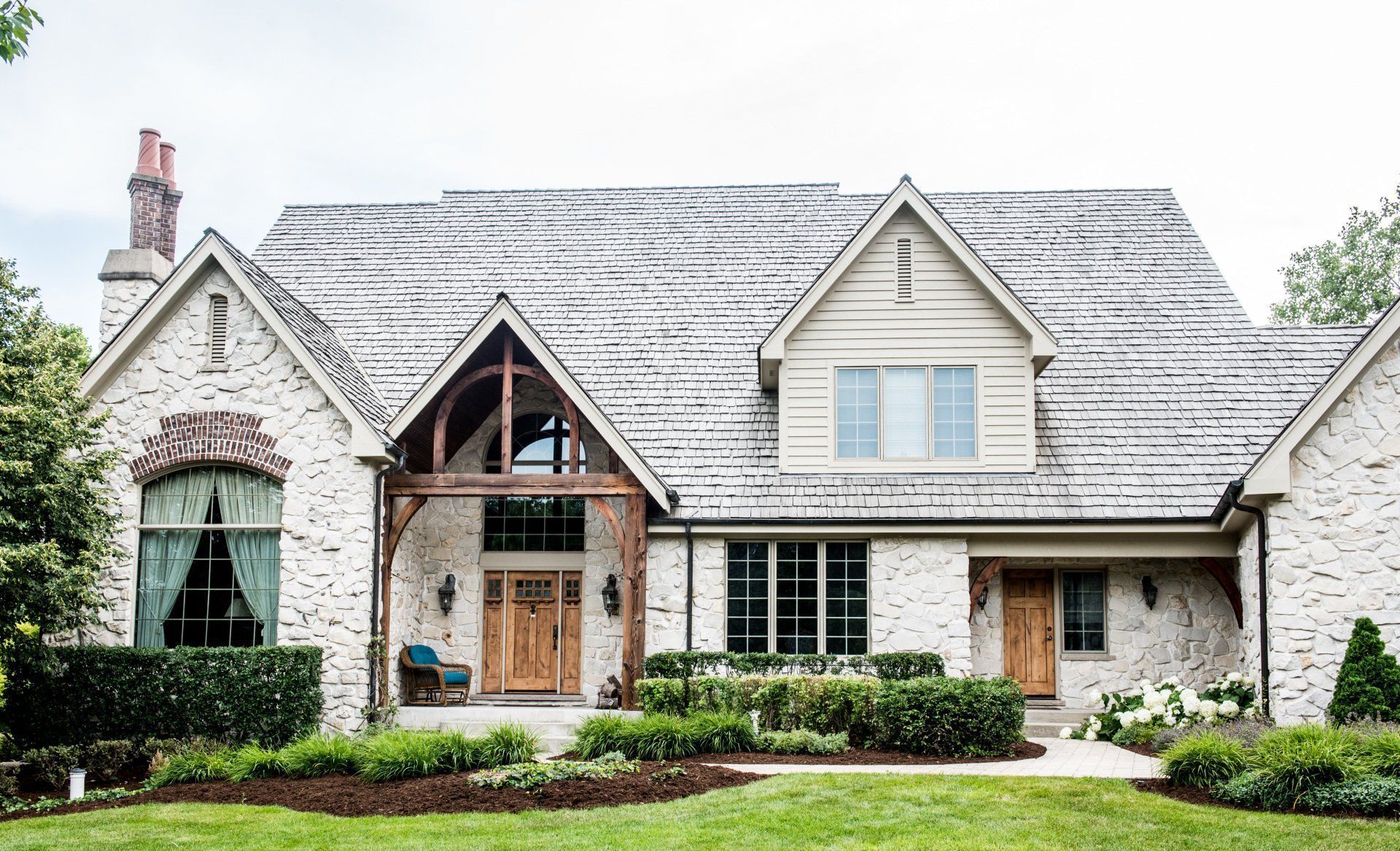 Stone house with steep gabled roof, large windows, and manicured front garden