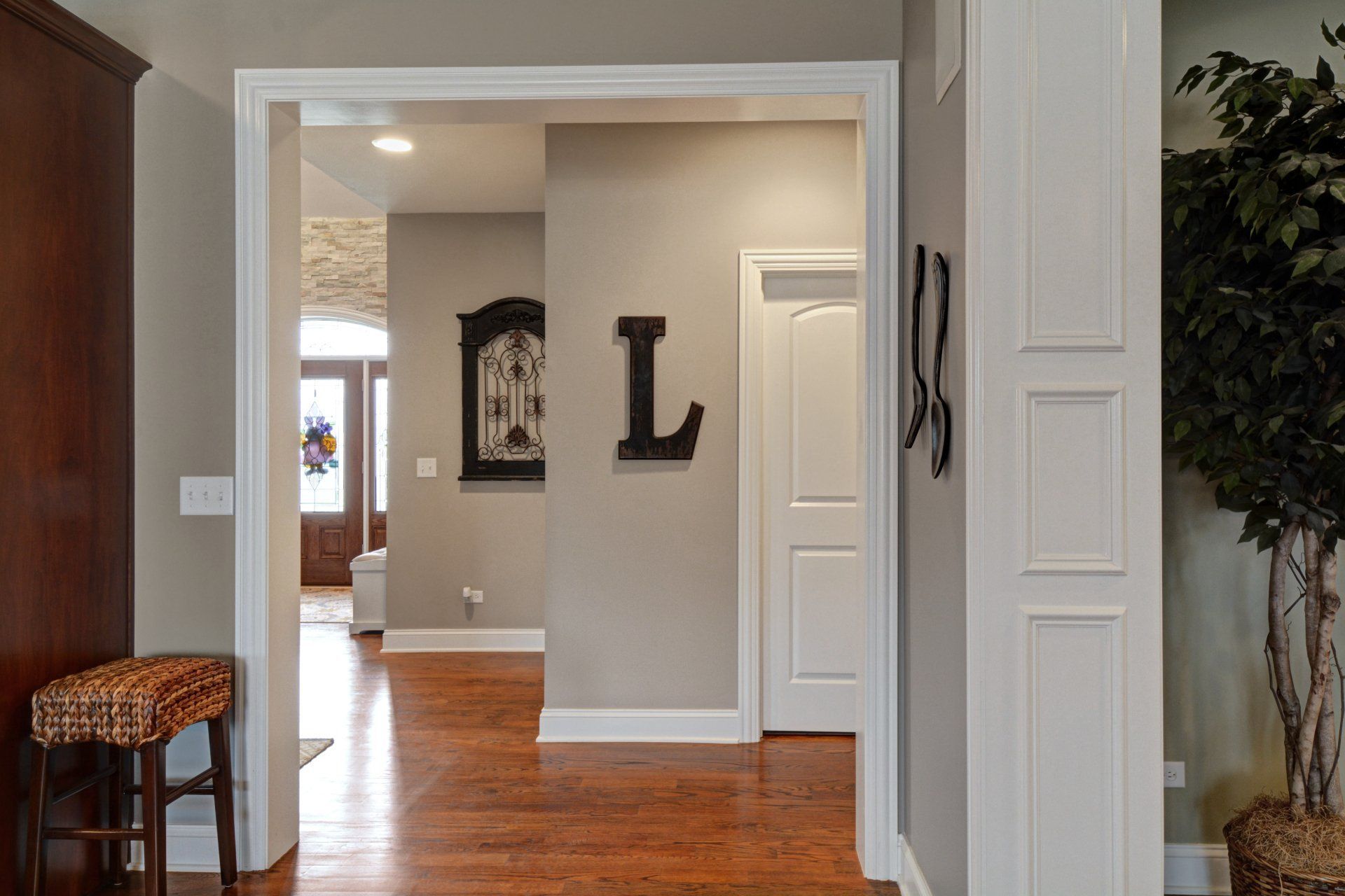 Hallway with hardwood floors, gray walls, and decorative letter art on the wall