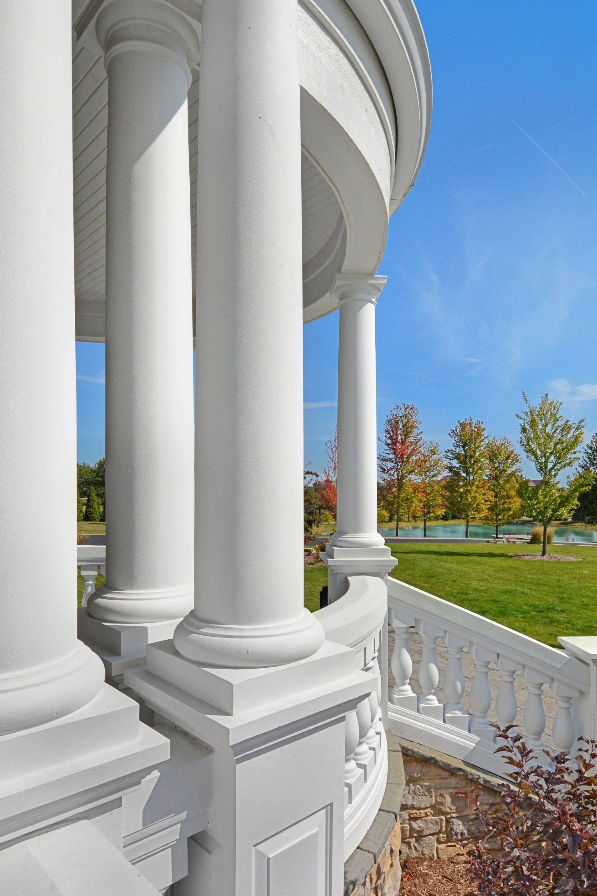 White columns on a porch overlooking a bright garden and blue sky