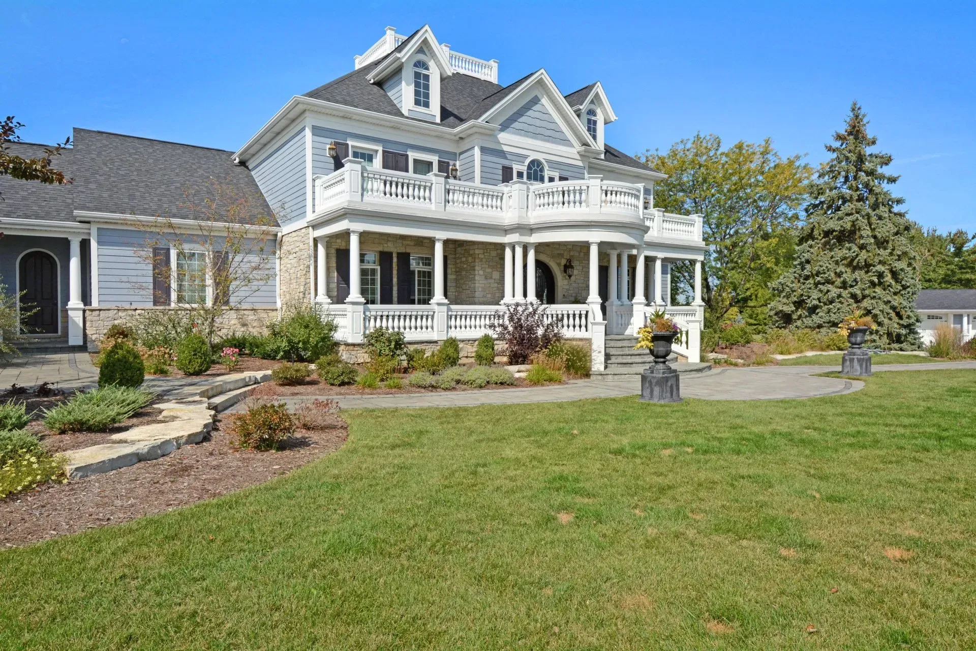 Large white Victorian-style house with a wraparound porch and a green lawn in front