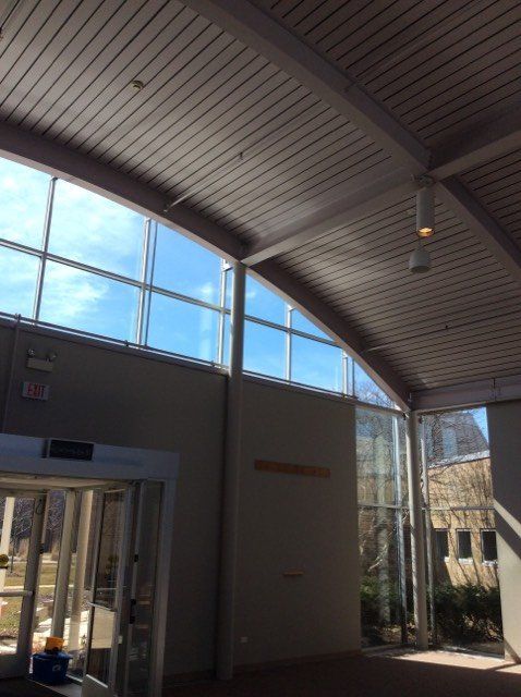 Interior view of a lobby with tall windows, curved ceiling, and sunlight streaming in