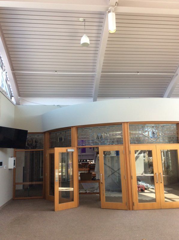 Interior entrance with open wooden and glass double doors beneath a high white ceiling