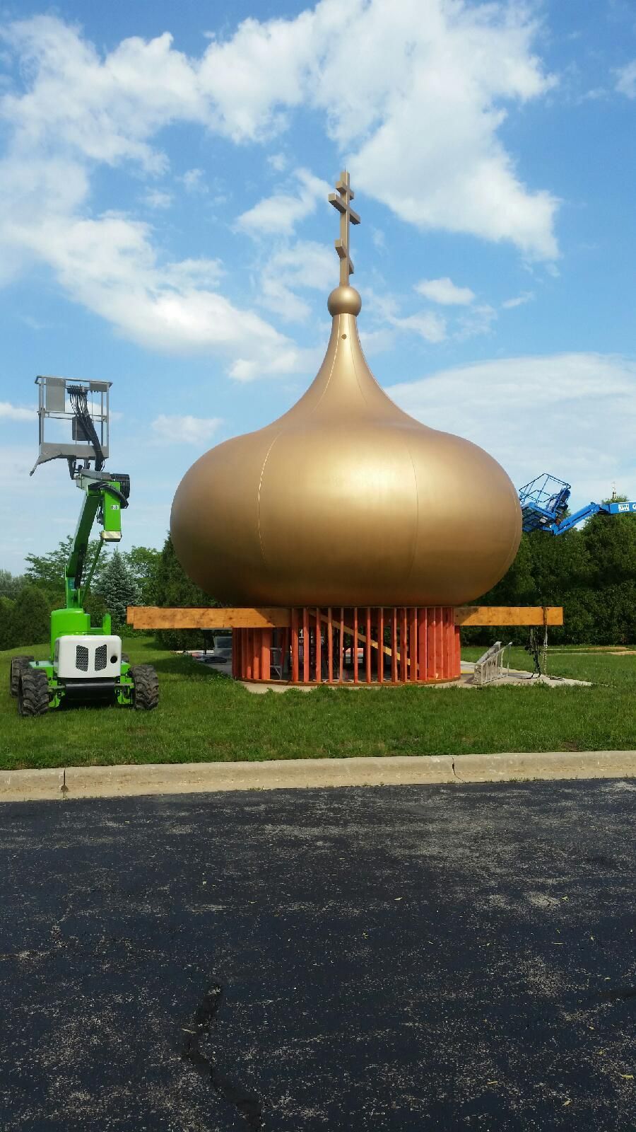 Golden onion-shaped dome monument on a grassy lawn under a blue sky