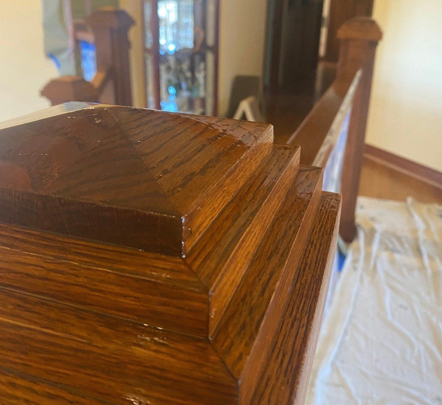 Close-up of a polished wooden furniture corner with layered trim, viewed in a room under renovation.