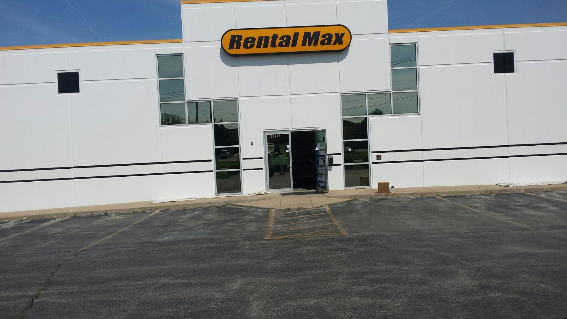 Front entrance of a Rent-A-Center store with white facade and parking lot in front
