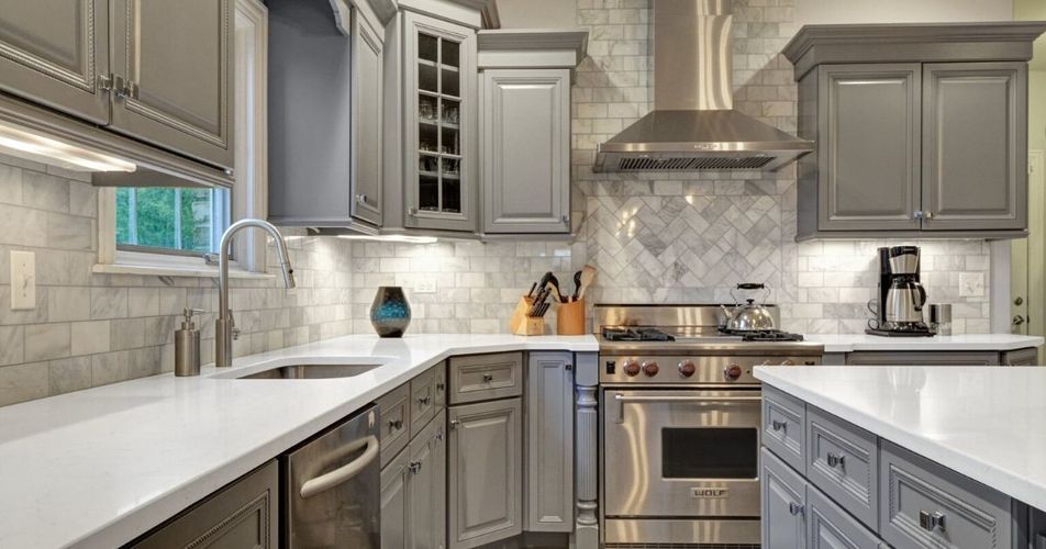 Modern gray kitchen with white countertops, stainless steel appliances, and a tiled backsplash