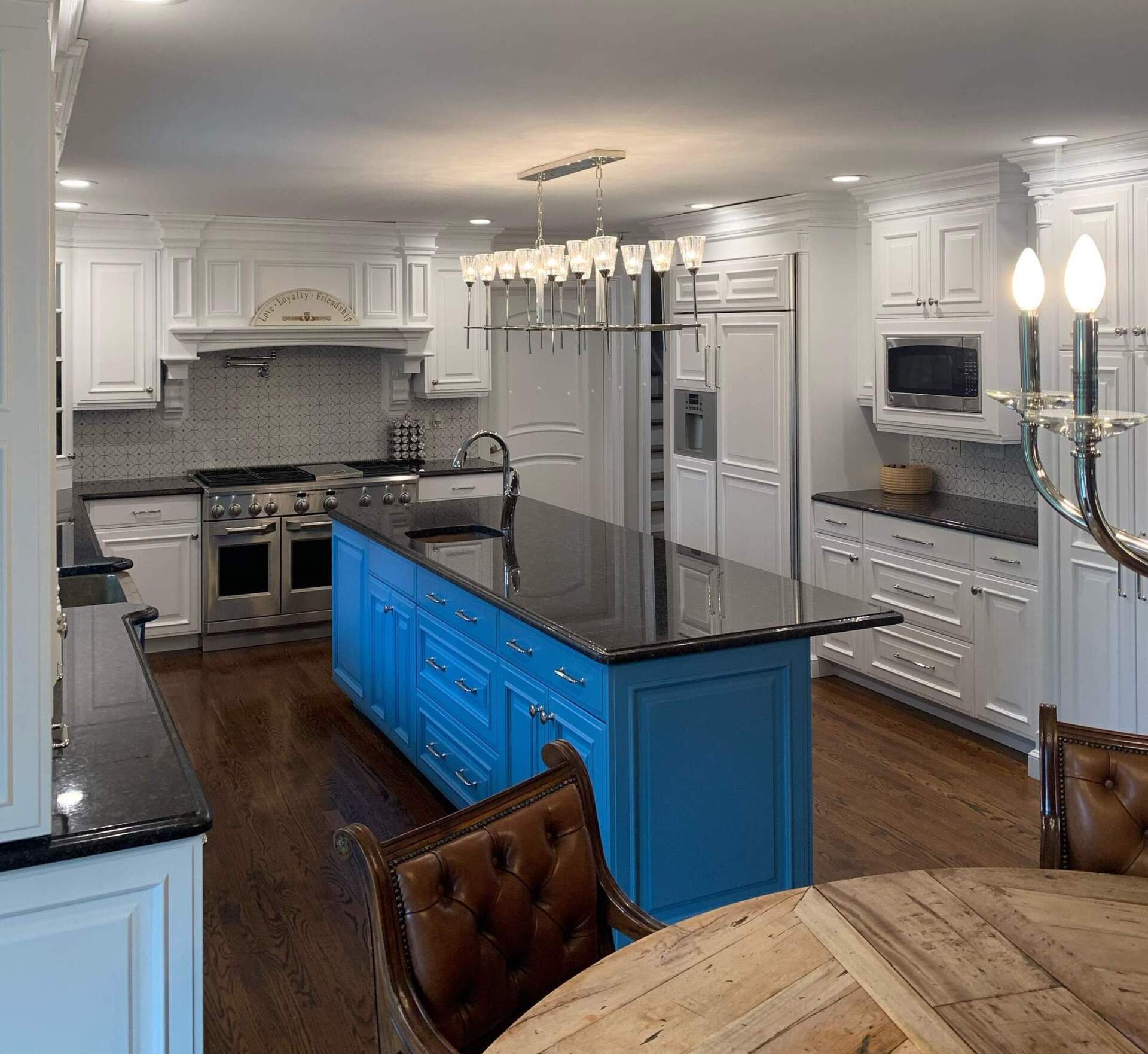 Bright modern kitchen with blue island, black countertops, white cabinets, and stainless steel appliances