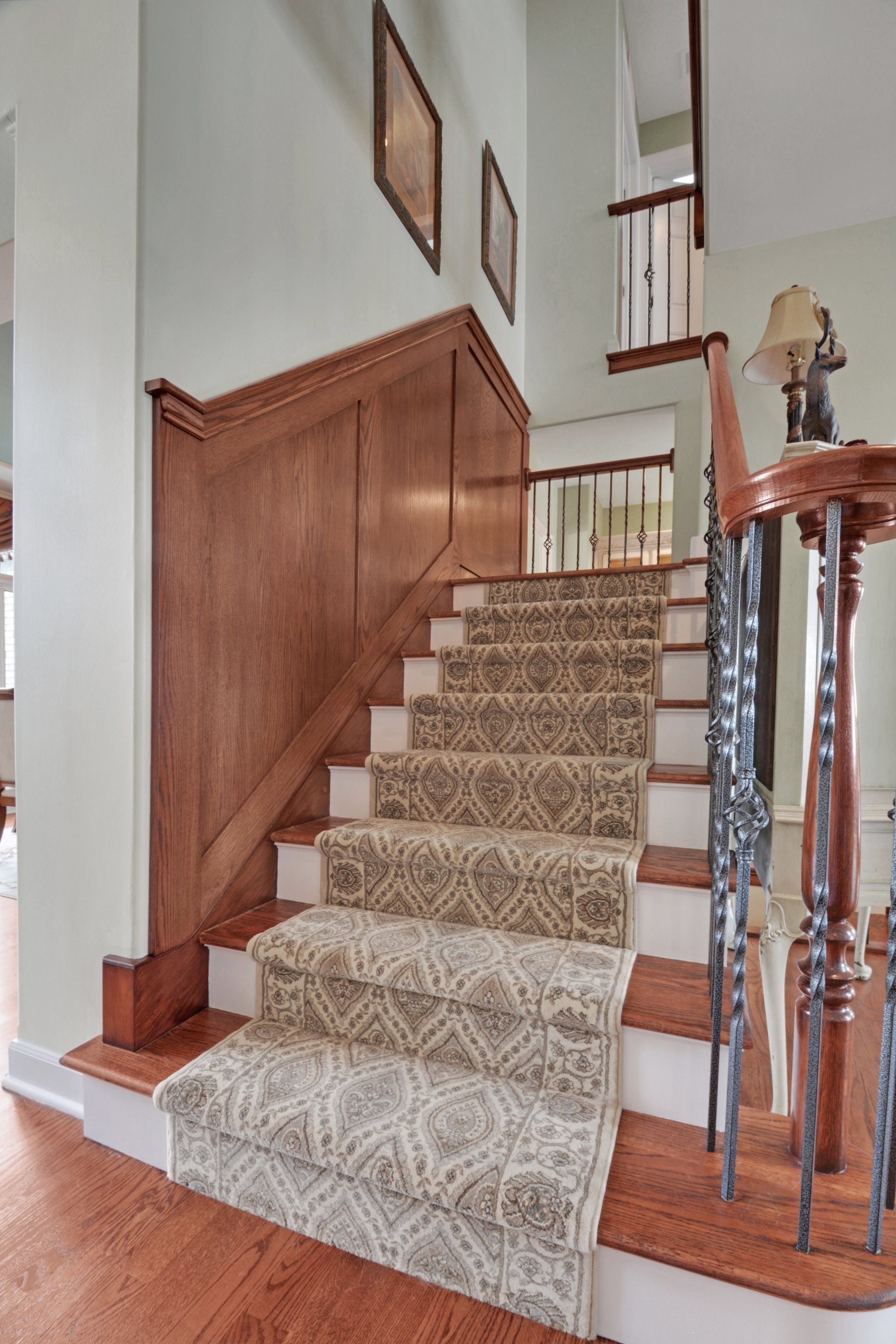 Carpeted staircase with wood banister and white walls in a home interior