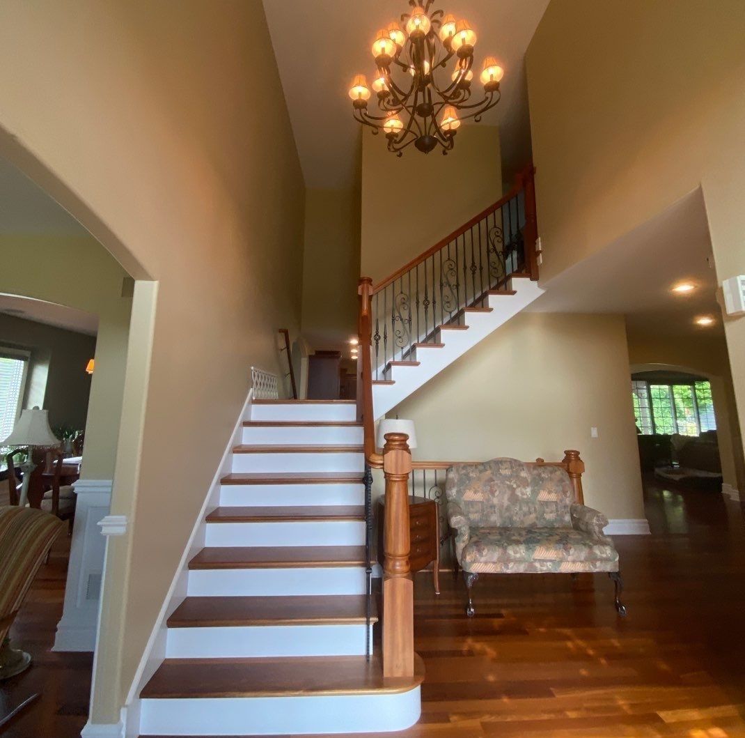 Entry foyer with staircase, chandelier, wood floors, and floral armchair