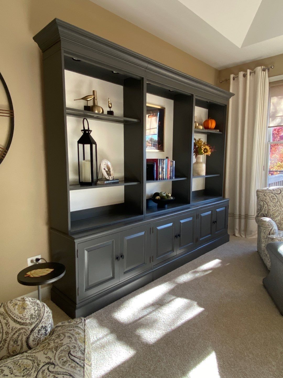 Dark wood entertainment cabinet with shelves and cabinets in a sunlit living room