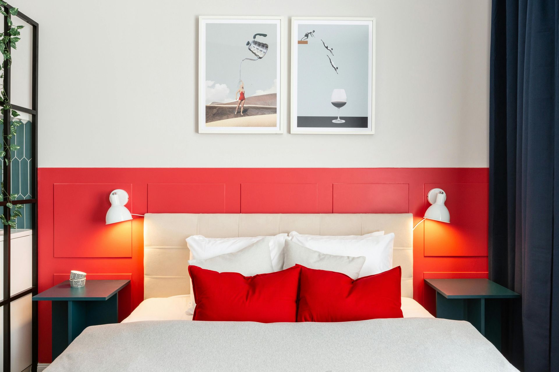 Modern bedroom with a red upholstered headboard, white bedding, bedside lamps, and framed wall art
