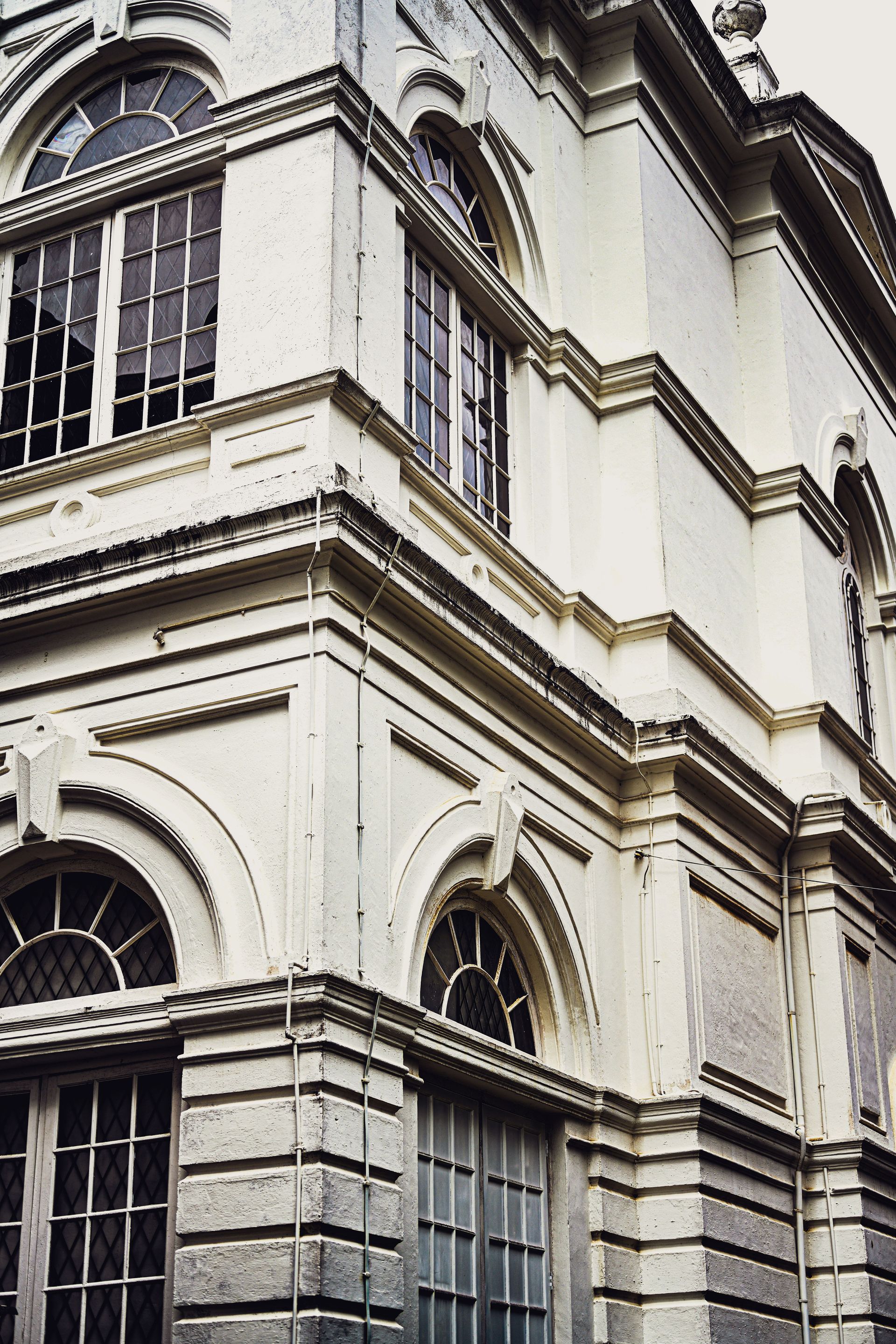 Corner view of a white historic building with arched windows and ornate stone detailing