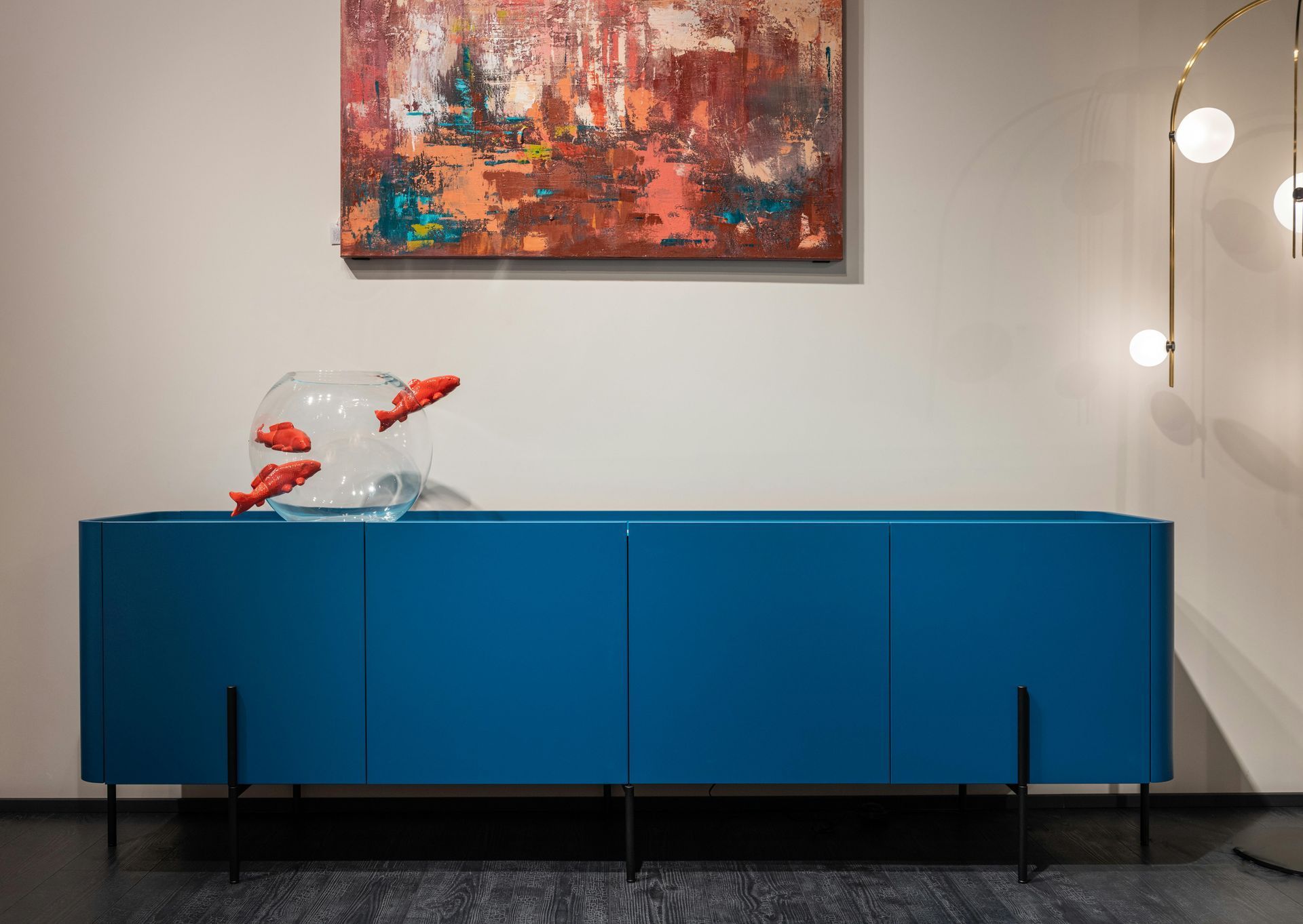 Blue sideboard with red fish sculpture beneath abstract painting in a modern room