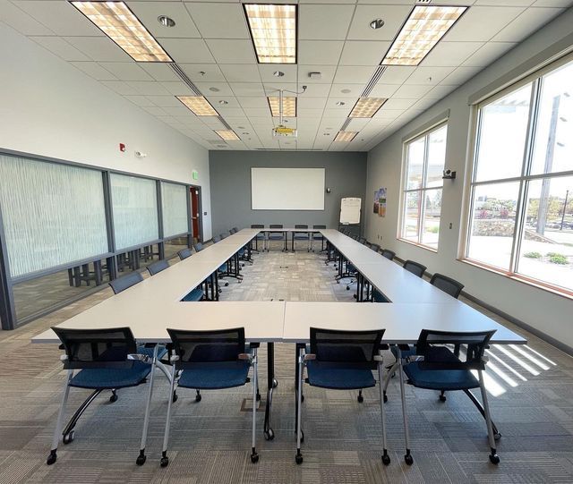 A conference room with tables and chairs and a projector screen