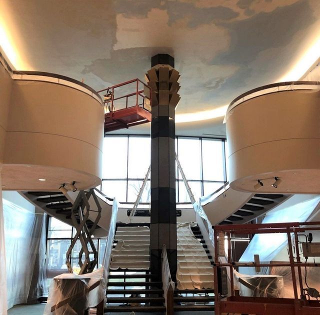 A room with stairs and a ceiling that has a picture of clouds on it