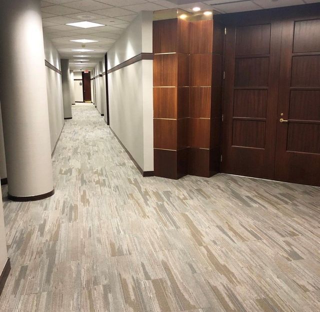 A long hallway with a carpeted floor and wooden doors
