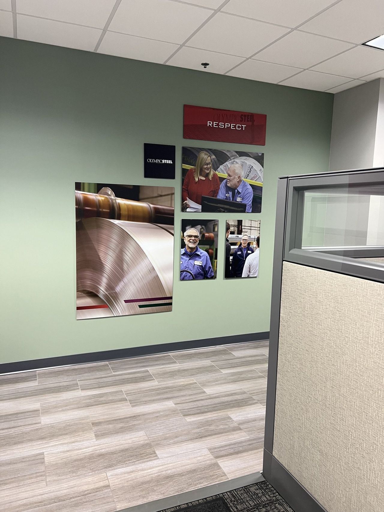 A cubicle in an office with pictures on the wall.