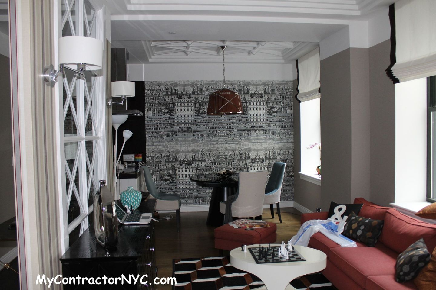 Modern living room with red sectional, white coffee table, patterned wallpaper, and dining area in back