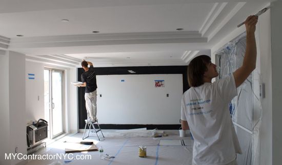 Workers painting walls in a bright room during home renovation.