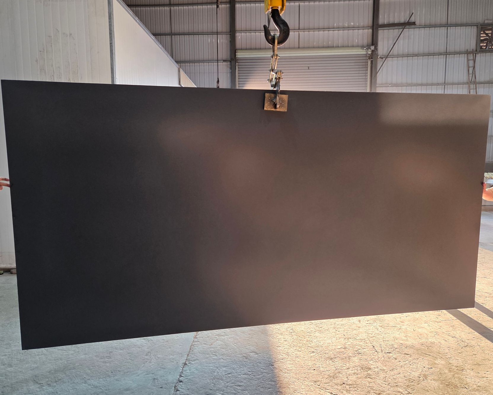 A Large, Solid Matte Black Slab Suspended by a Crane Hook — Better Stone in Caloundra West, QLD
