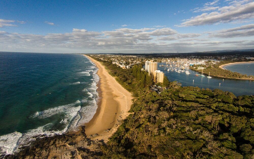 An Aerial View Of A Beach At Sunset With A Building In The Distance — Better Stone in Gold Coast, QLD