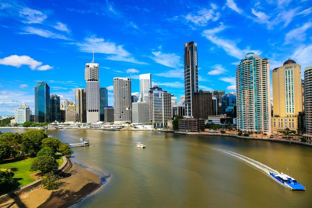 A Boat is Going Down a River in Front of a City Skyline — Better Stone in Brisbane, QLD