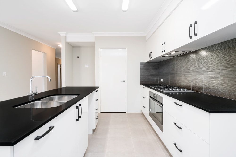 A Kitchen With Black Counter Tops and White Cabinets — Better Stone in Caloundra West, QLD