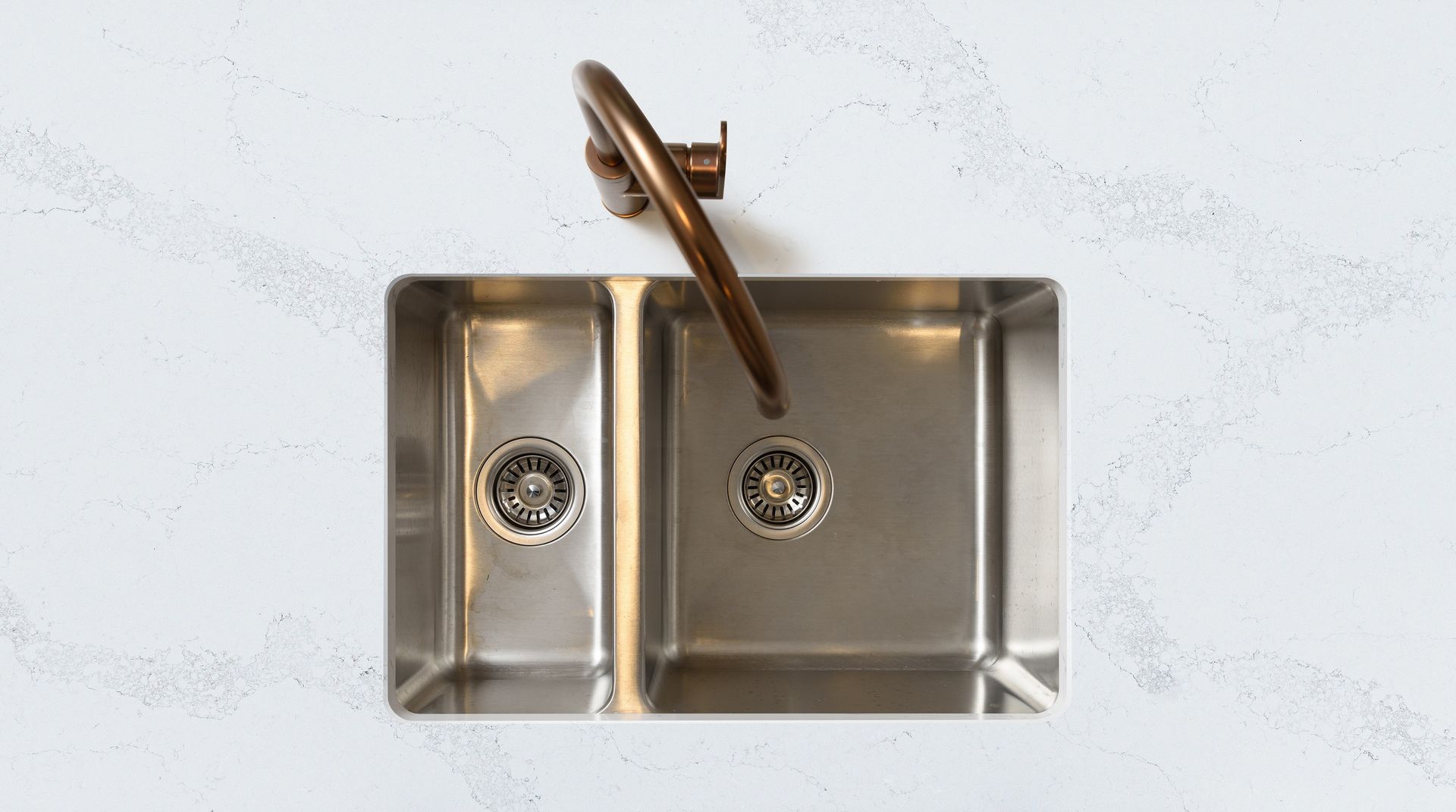 A Stainless Steel Kitchen Sink With a Copper Faucet on a White Counter Top — Better Stone in Caloundra West, QLD