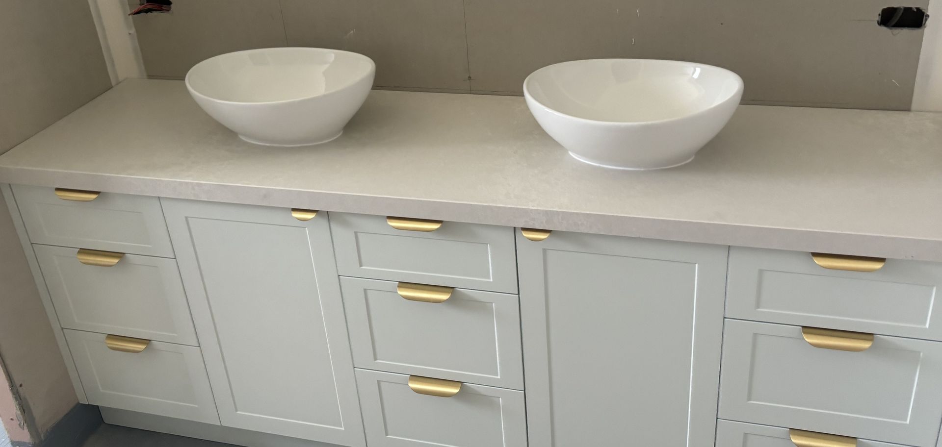 Light blue bathroom vanity with two white sinks and gold hardware.