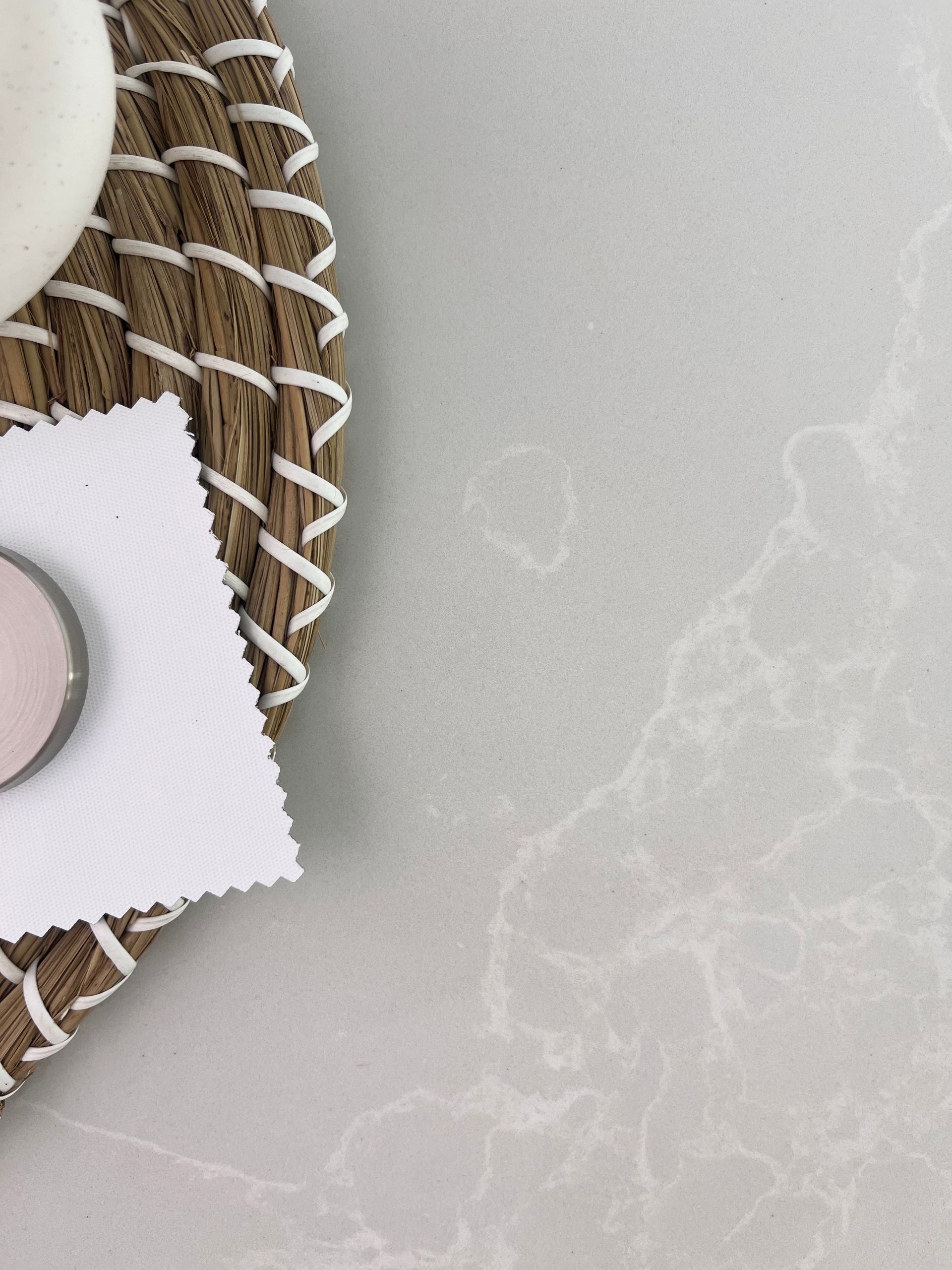 Wicker tray with white soap and a white swatch on a marble-patterned countertop.