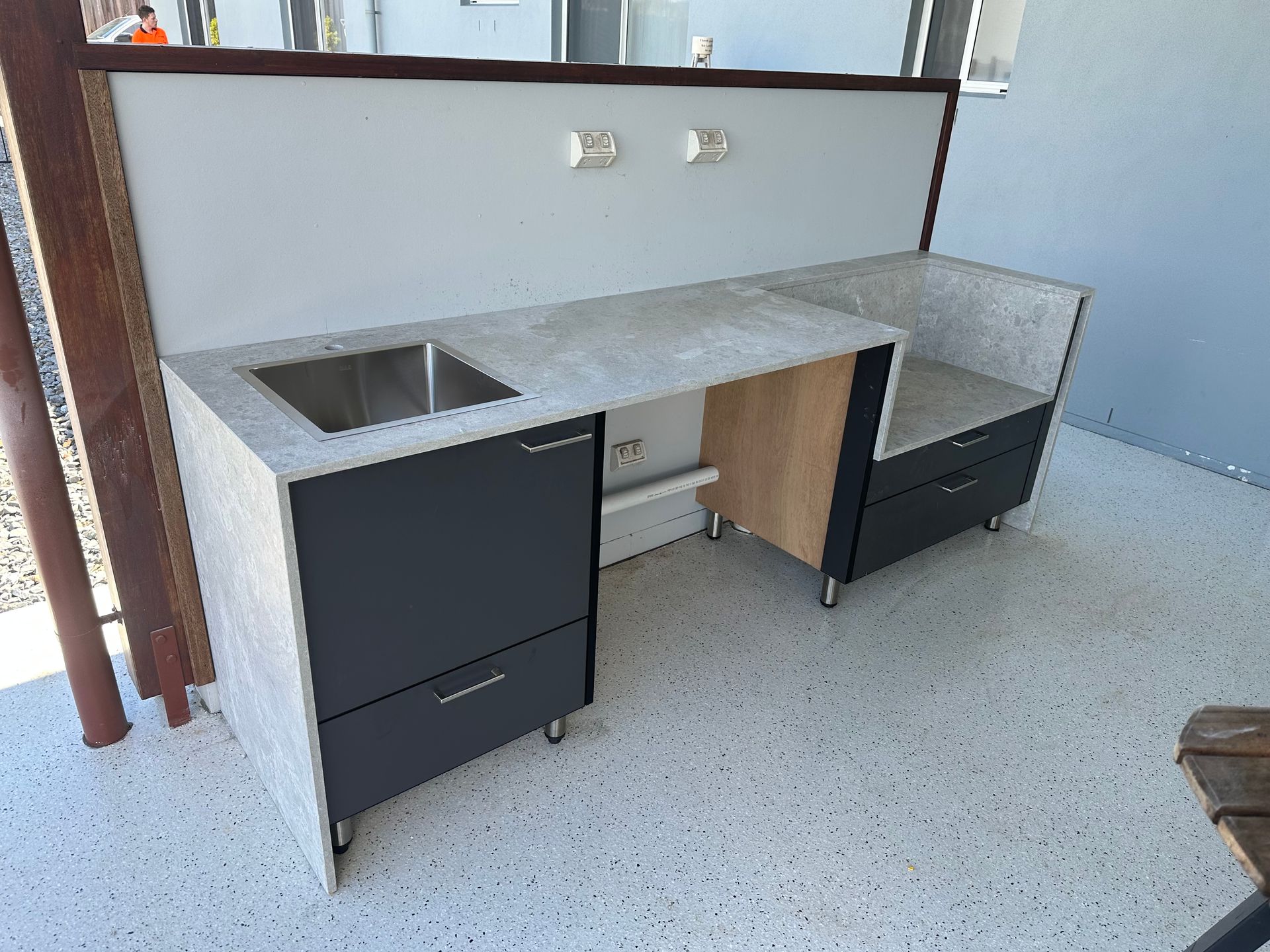 Outdoor kitchen with gray countertop, sink, and black cabinets.