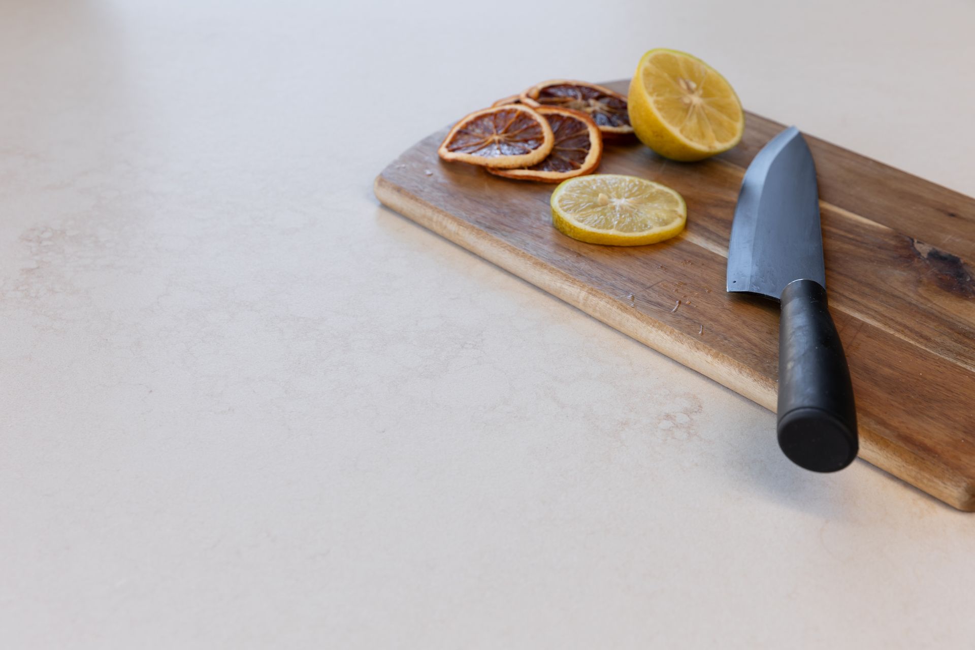 Wooden cutting board with sliced lemons and knife.