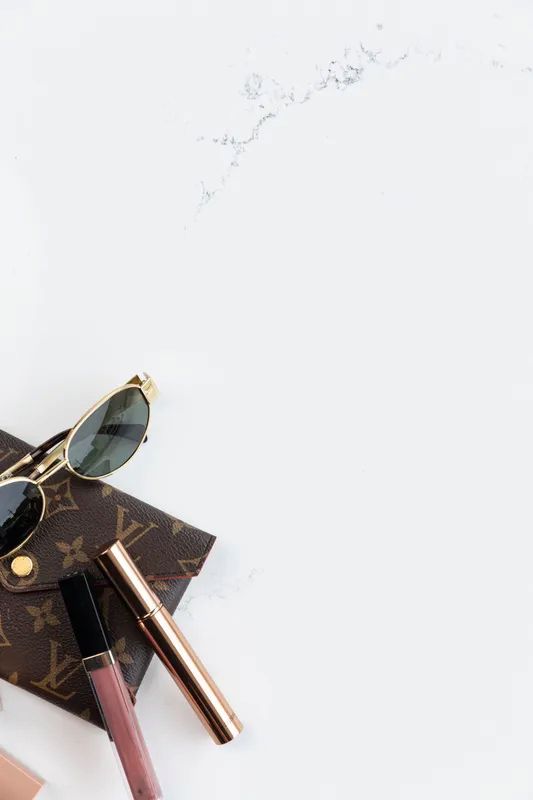 A Pair of Sunglasses, a Lipstick, and a Purse Are on a White Surface — Better Stone in Caloundra West, QLD
