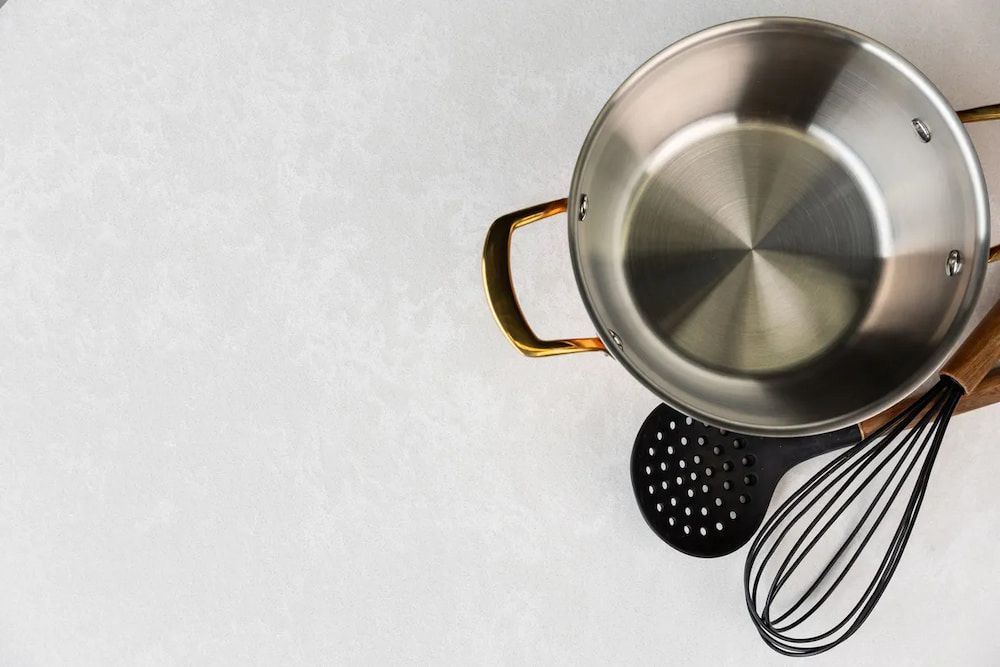 A Pot, Whisk, Strainer and Ladle on a White Surface — Better Stone in Caloundra West, QLD