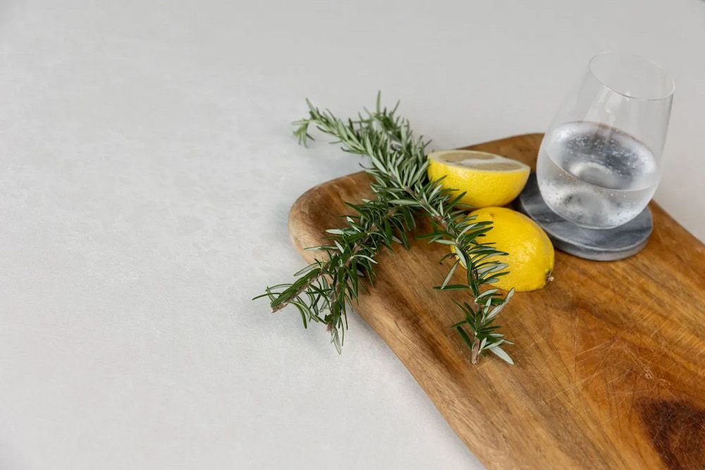 A Wooden Cutting Board With Lemons, Rosemary and a Glass of Water on It  — Better Stone in Caloundra West, QLD