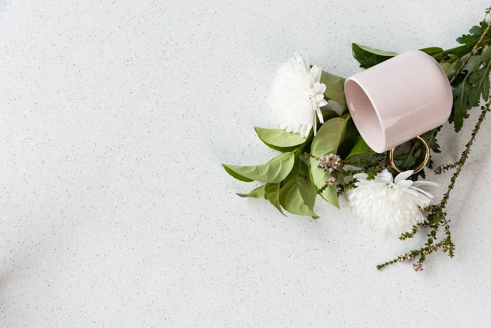 A Cup of Coffee, Flowers and Leaves on a White Surface — Better Stone in Caloundra West, QLD