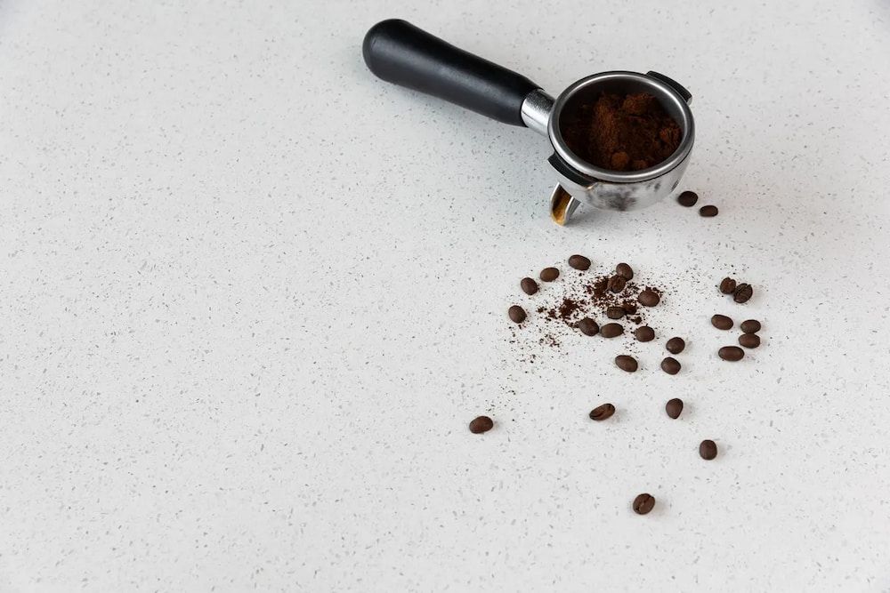 A Spoon of Coffee Powder and Coffee Beans on a White Surface — Better Stone in Caloundra West, QLD