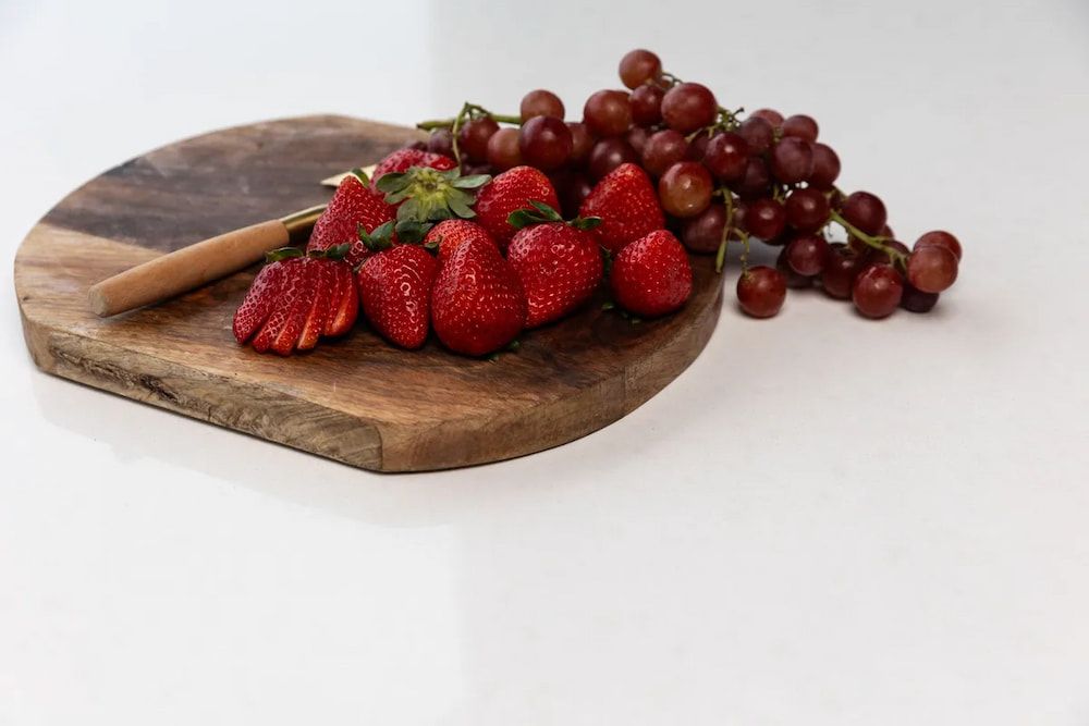 Strawberries and Grapes Are on a Wooden Cutting Board — Better Stone in Caloundra West, QLD