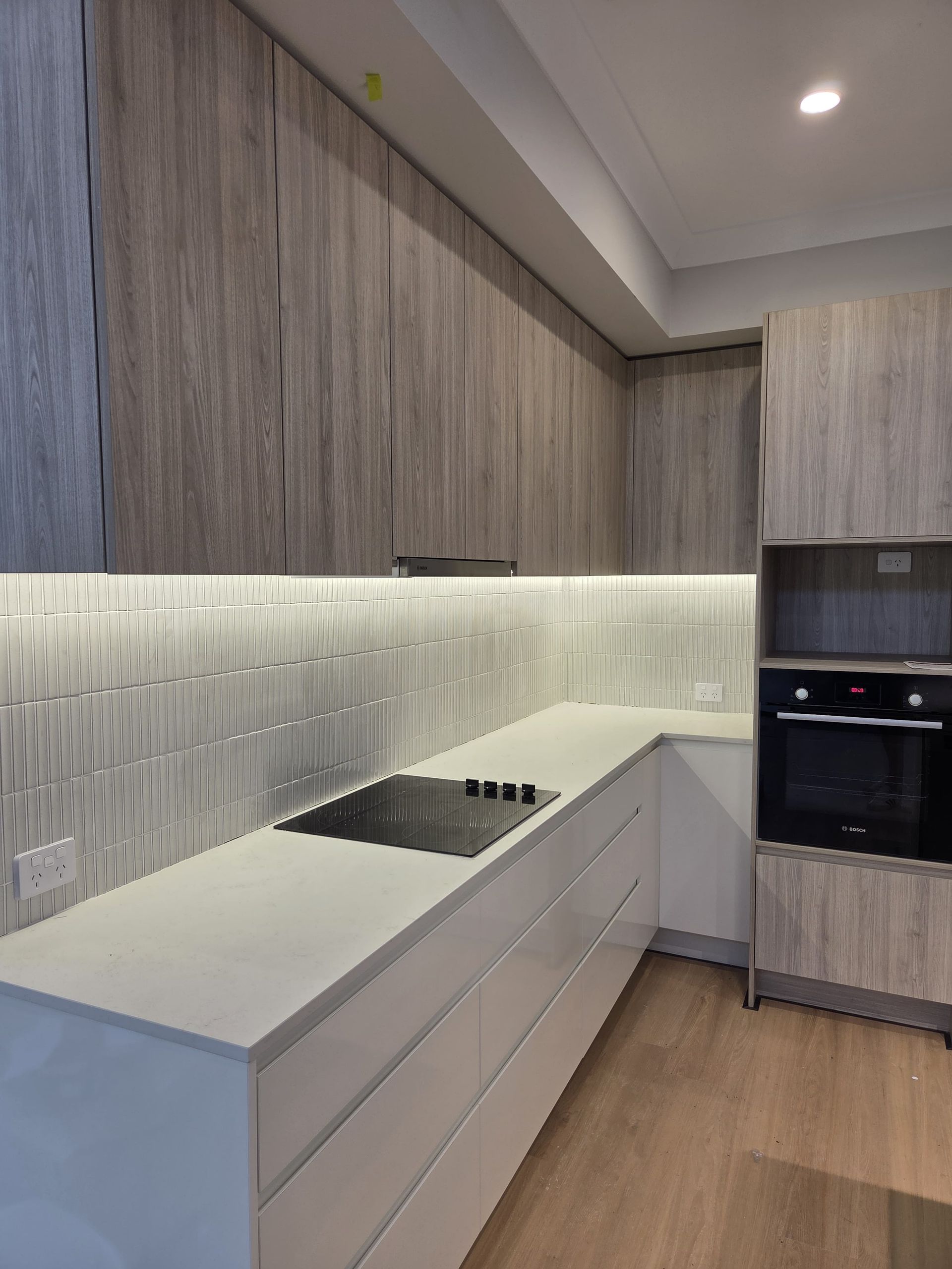 A Modern Kitchen Featuring Light Wood-grain Cabinets and Textured Backsplash Tiles — Better Stone in Caloundra West, QLD