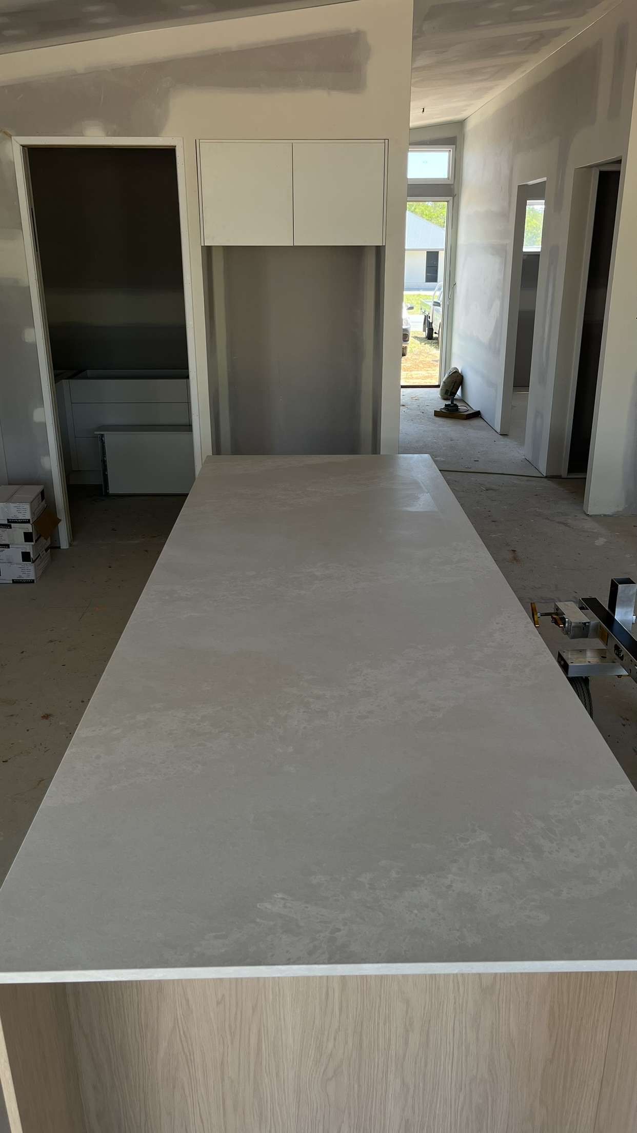 Construction site: large countertop, unfinished walls, doorway, and sunlight.