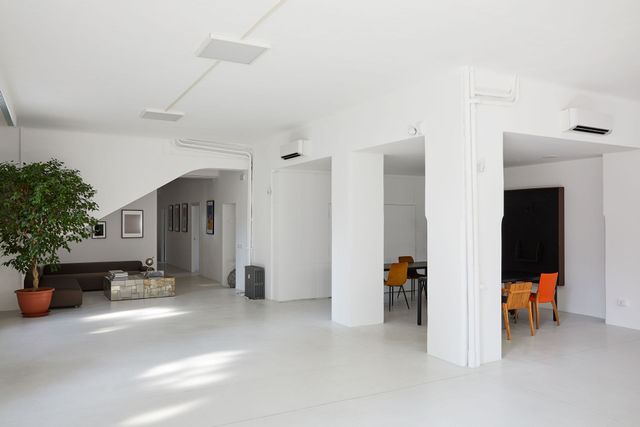 Bright white open-plan interior with columns, seating area, and small dining table.