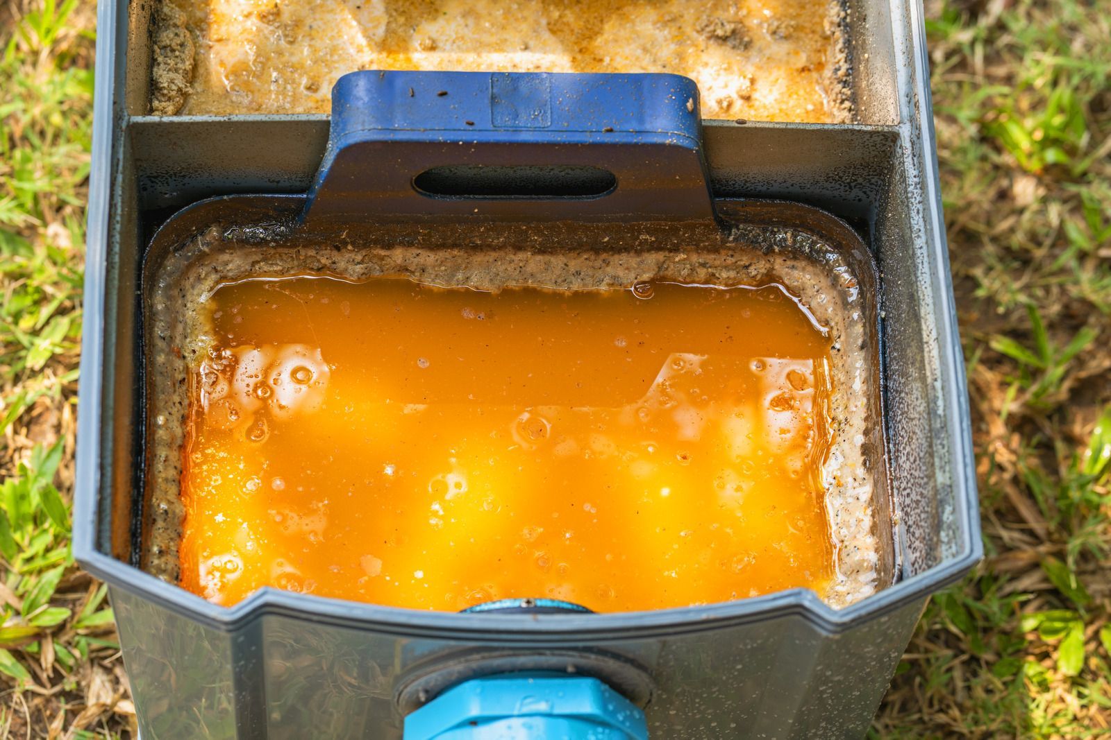 Open box filled with orange liquid beside muddy ground outdoors