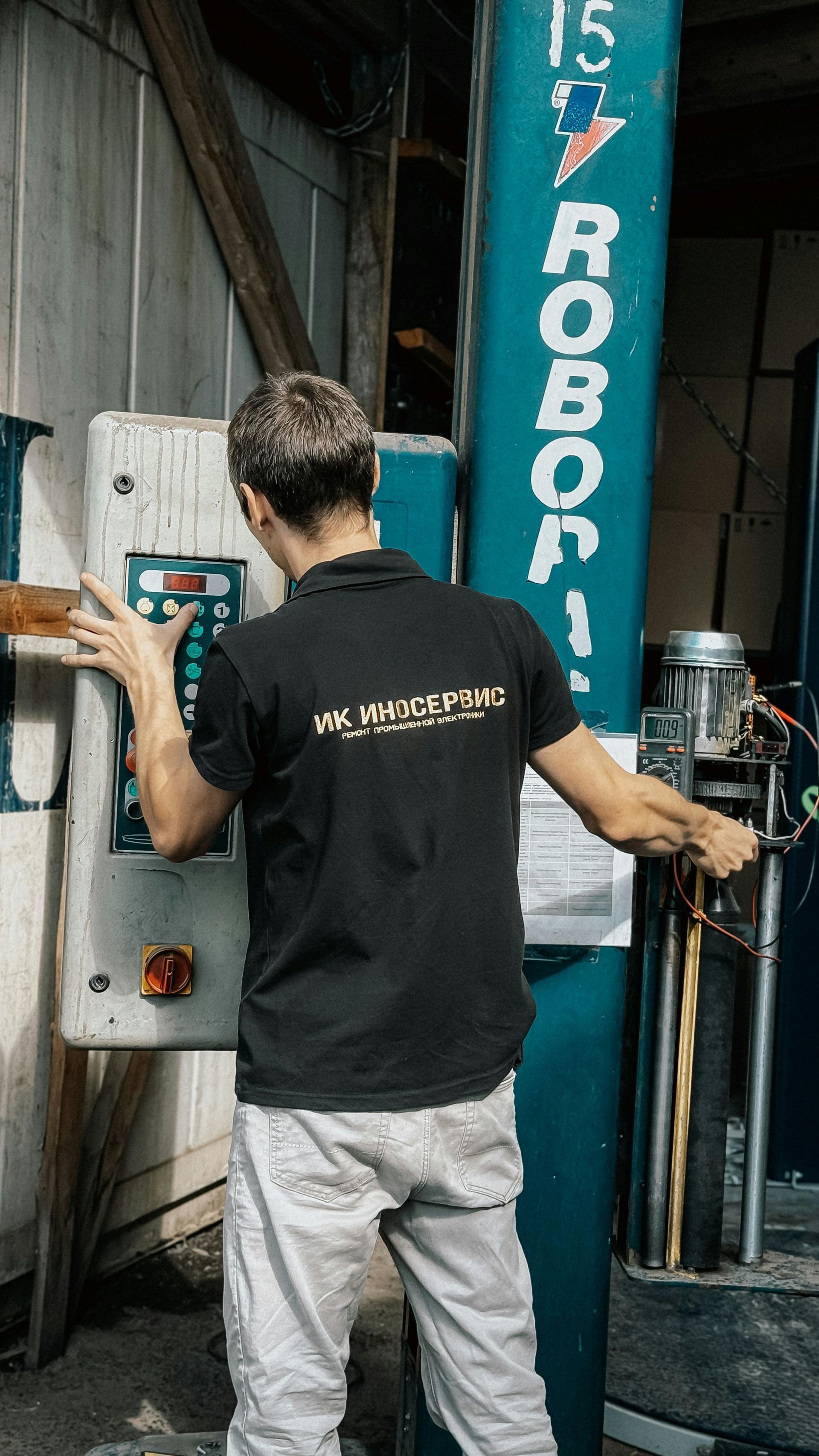 Mechanic in black shirt operating machinery control panel in garage.