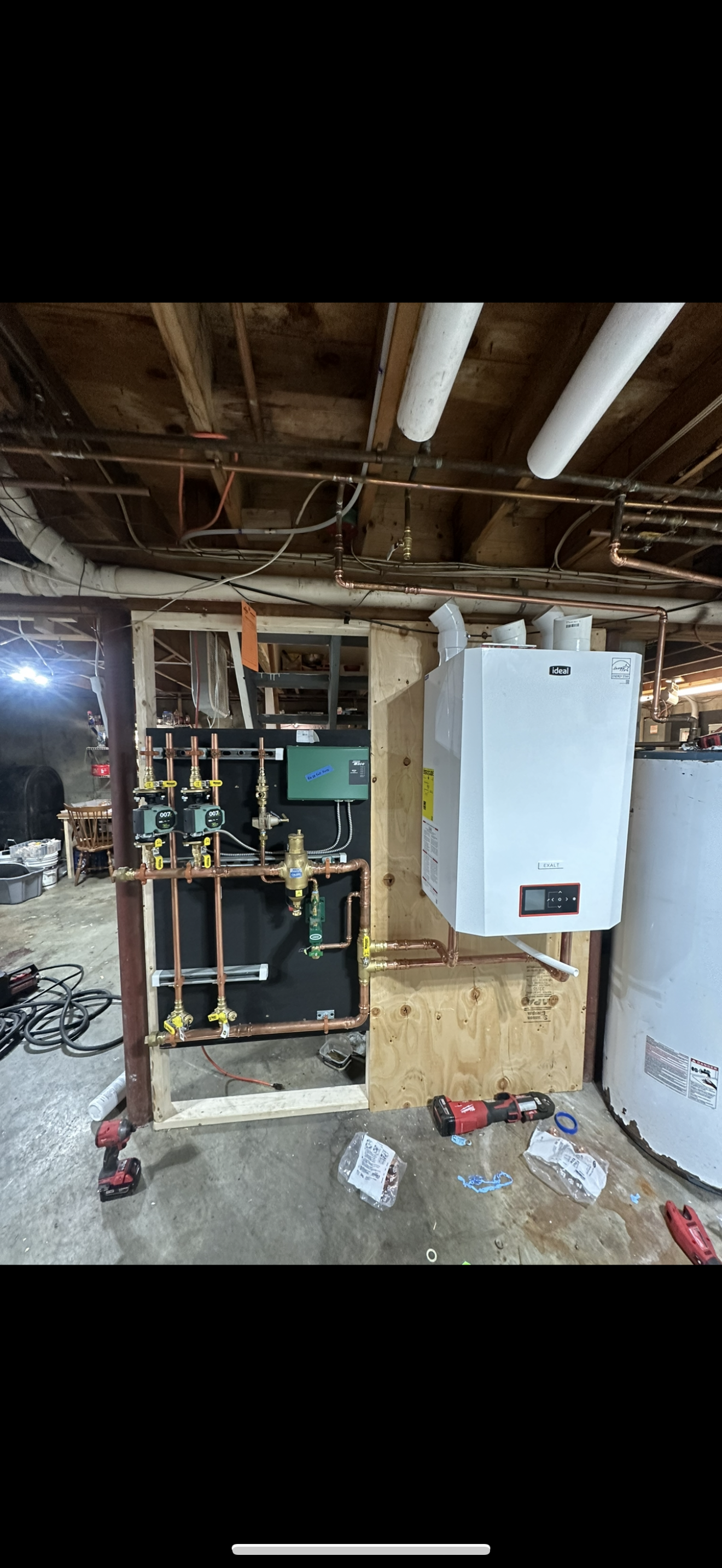 Basement utility room with exposed pipes, furnace, water heater, and construction clutter