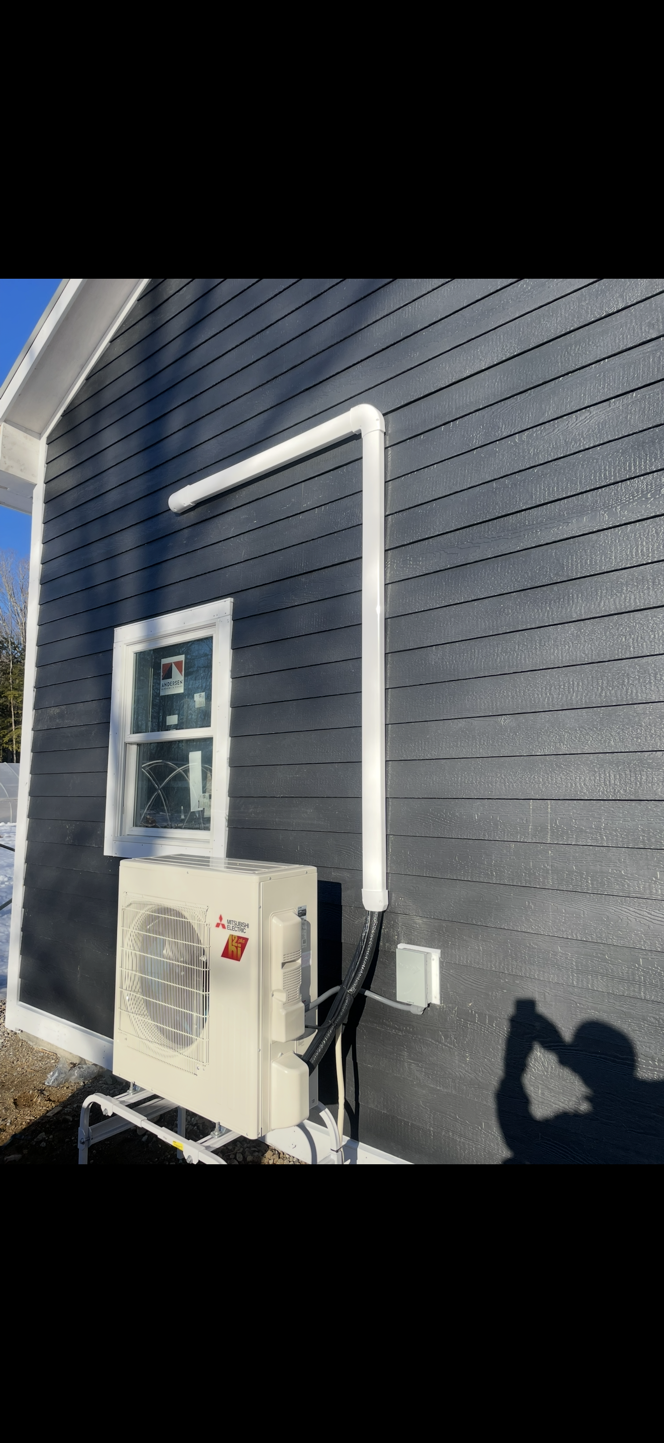 Dark blue house exterior with white trim, a window, and a mounted air conditioner unit.